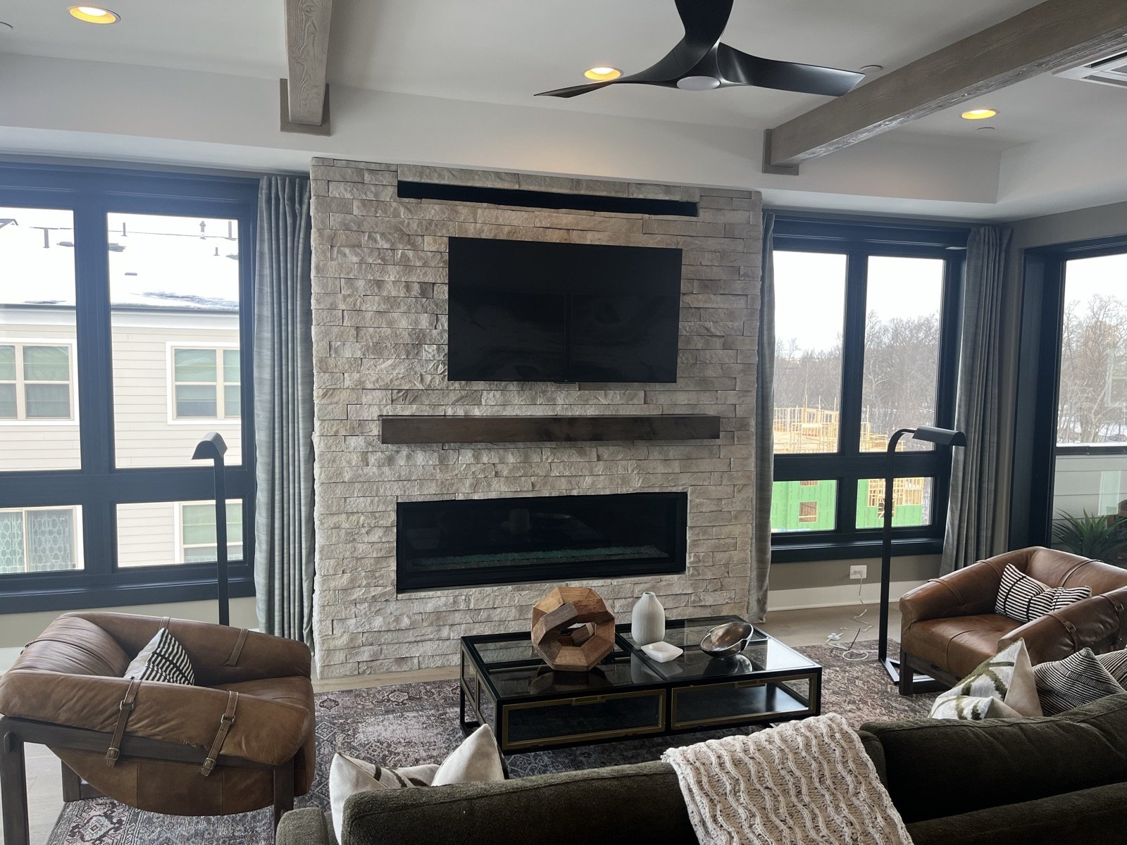 Open living room with stone fireplace remodeled by Donya LLC